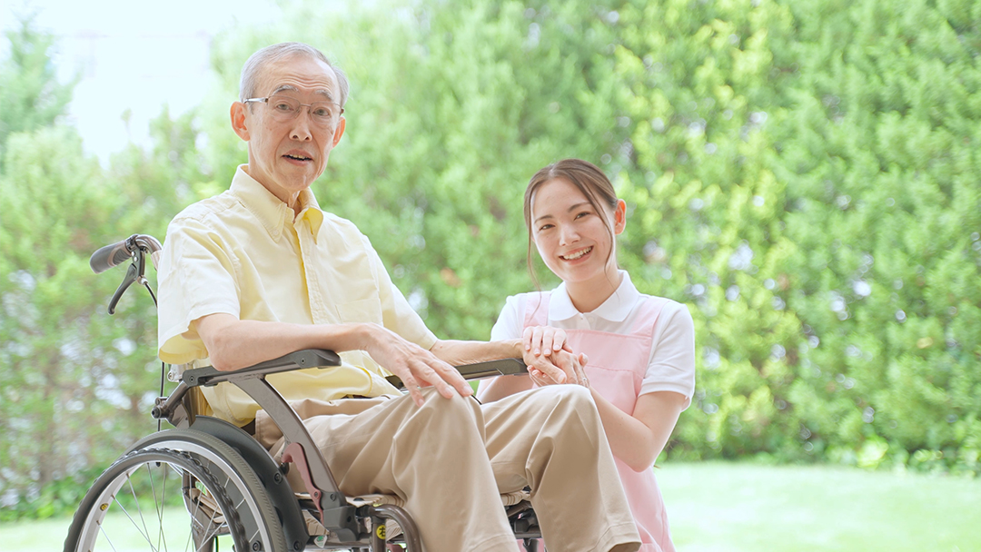 휠체어에 앉은 사람과 옆에서 손을 잡고 있는 사람 사진