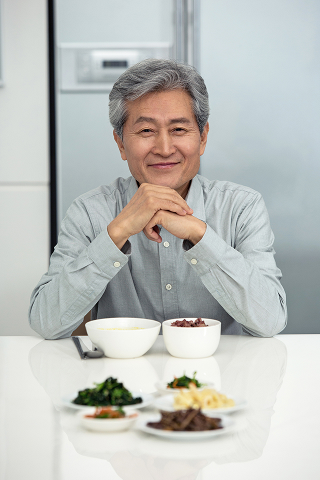 식사를 차려놓은 식탁에 앉아 미소 짓는 남자 사진 